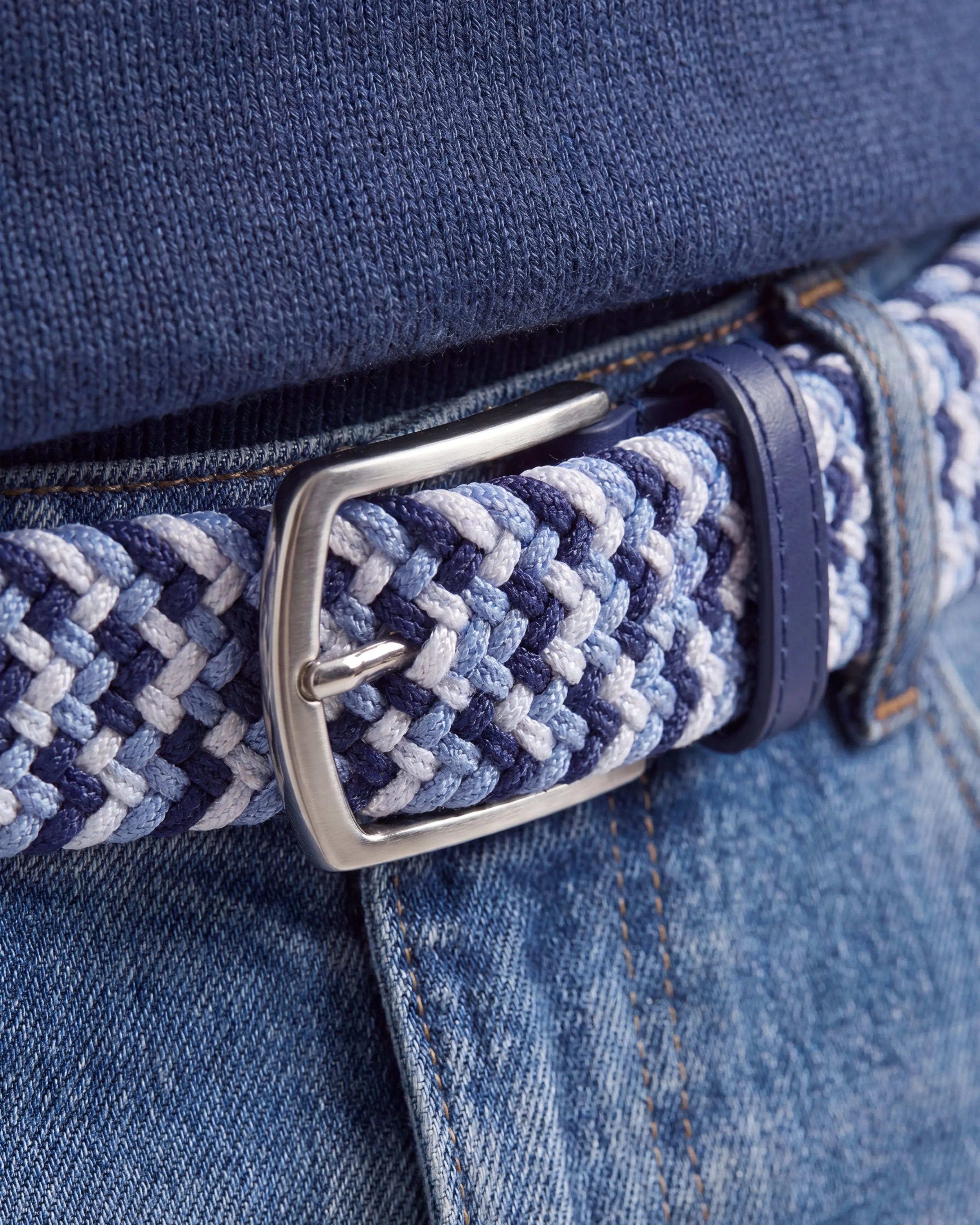 Detaljbild på flätat bälte ljusblå tillsammans med jeans